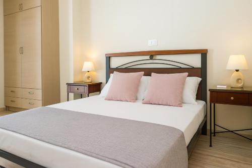a bedroom with a large bed with pink pillows at Cozy flats in an olive grove by the sandy beach in Kánalos
