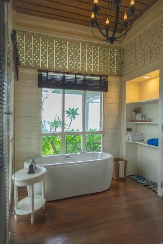 a large bath tub in a room with a window at De Chaochom Hua Hin in Hua Hin