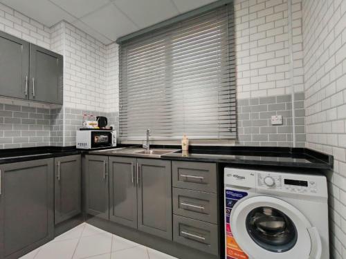 a kitchen with a washing machine and a sink at Baithans 24 Furnished Apartments Hotel LLC in Ajman 