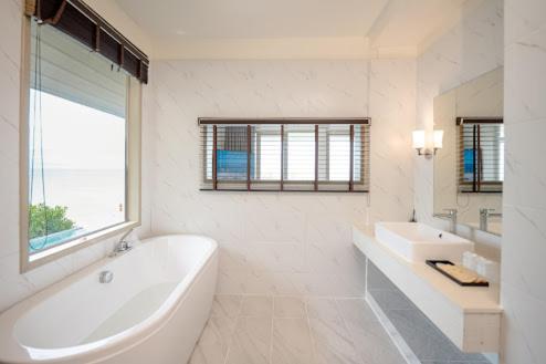 a white bathroom with a large tub and a sink at De Chaochom Hua Hin in Hua Hin
