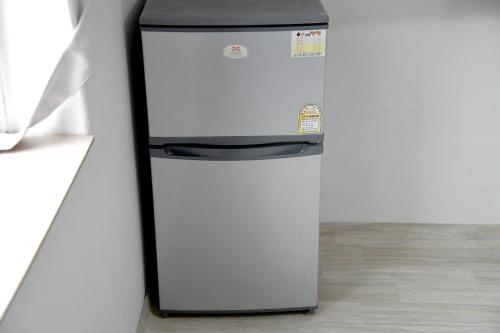a white refrigerator sitting next to a wall at Sorak Hostel in Sokcho