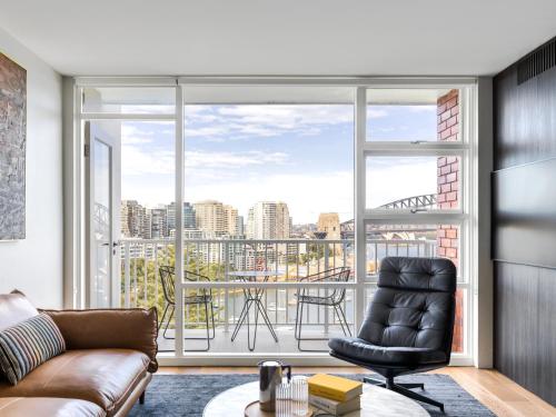 a living room with a couch and a large window at Panoramic Sydney Harbour Views from Luxury 1-Bedroom Apartment in McMahons Point in Sydney