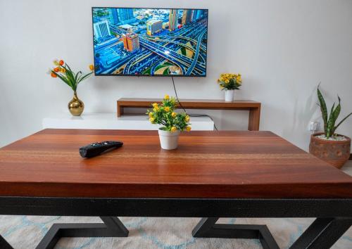 a wooden table with a remote control and flowers on it at Perfect Palm Condos-N12 in Nakuru