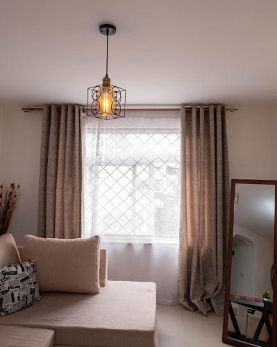 a living room with a couch and a window at Perfect Palm Condos-N12 in Nakuru