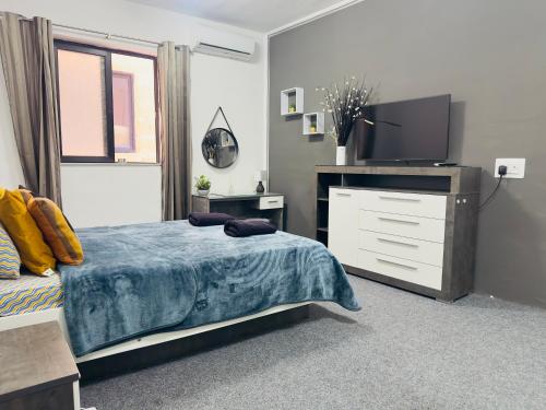 a bedroom with a bed and a dresser with a tv at Sea Breeze Retreat - Comfort Apartments in the Heart of Sliema in Sliema