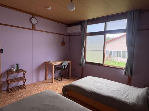 a bedroom with two beds and a desk and a window at ペコレラ学舎 Teacher House in Yakumo