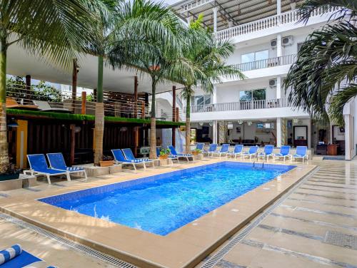 a pool with chairs and palm trees and a building at Golden Hotel in Nungwi