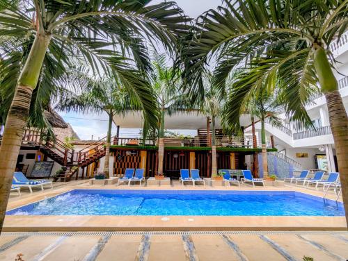a pool with palm trees and chairs and a building at Golden Hotel in Nungwi