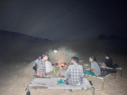 a group of people sitting around a fire on the beach at Star View Guest House & Safari in Jaisalmer
