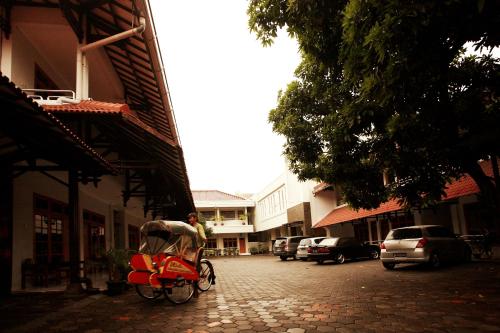a man riding a red rickshaw down a street at Syariah Arini Hotel in Solo
