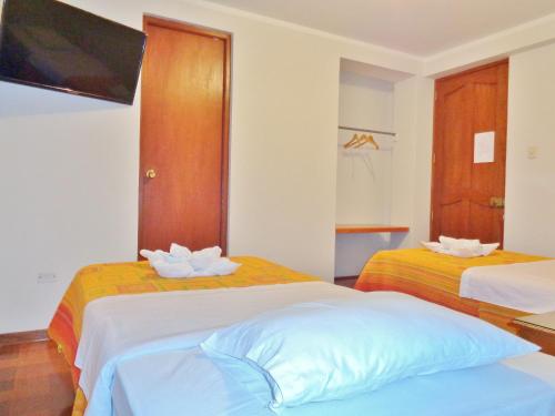 a bedroom with two beds and a flat screen tv at Hostal Silpay in Tacna