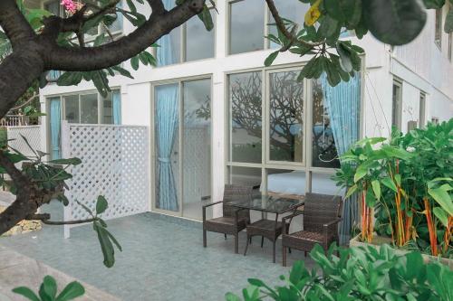 a patio with two chairs and a table and windows at De Chaochom Hua Hin in Hua Hin