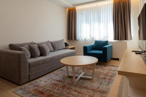 a living room with a couch and a table and a chair at Zepterme Spa&Wellness Luxury Apartments member of Zepter hotels in Vrnjačka Banja