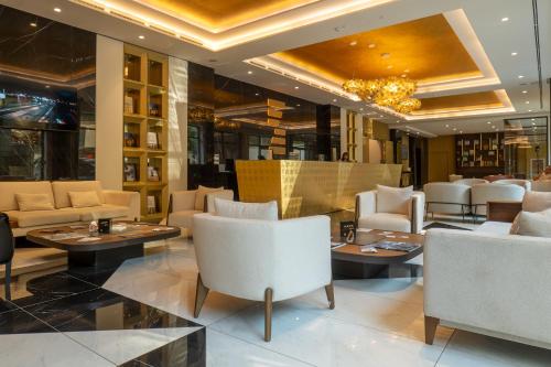 a restaurant with white chairs and tables and a chandelier at Zepterme Spa&Wellness Luxury Apartments member of Zepter hotels in Vrnjačka Banja