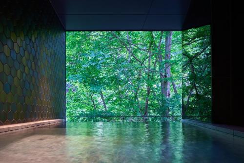 a room with a large window with trees in the background at Shima Onsen Yuzuriha in Nakanojo
