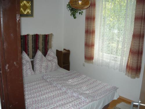 sypialnia z łóżkiem z poduszkami i oknem w obiekcie Judit Vendégház a Balatonnál w mieście Vonyarcvashegy