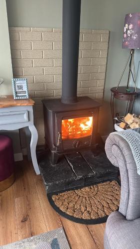 a wood stove in a living room with a couch at Country Cosy Cottage in Bailieborough