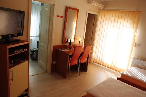 a room with a bed and a desk with a television at Vila DeLux in Negotin
