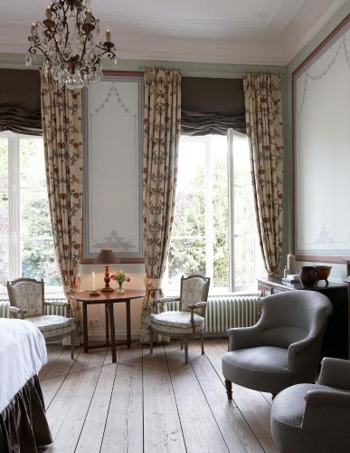 a bedroom with a table and chairs and windows at B&B De Corenbloem Luxury Guesthouse - Adults Only in Bruges