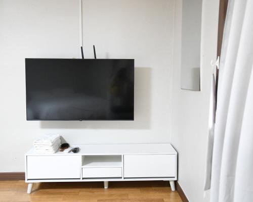 a white entertainment center with a flat screen tv on a wall at Sorak Hostel in Sokcho