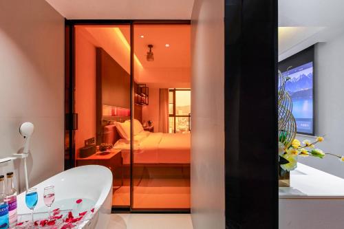 a bathroom with a tub and a bed in a room at 西双版纳熙源国际酒店 in Jinghong