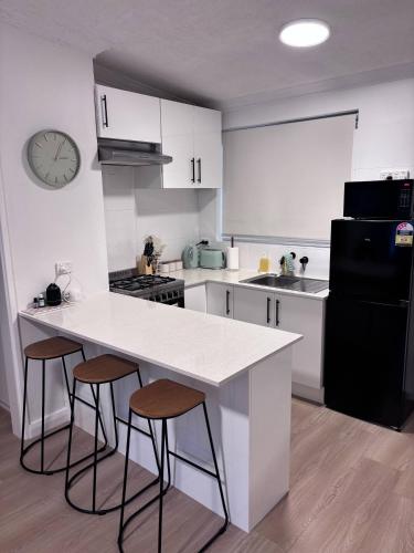 a kitchen with a white counter and two stools at Cosy Perth retreat in Perth