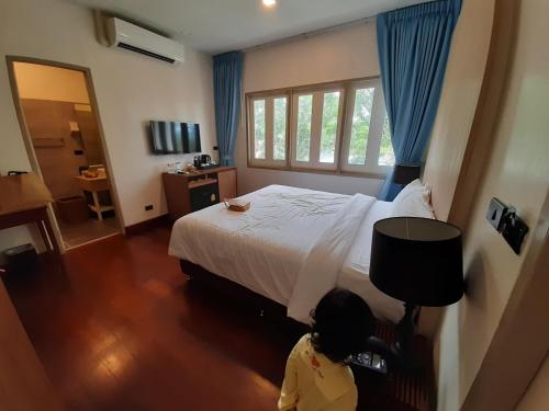 a little girl standing in a bedroom with a bed at De Chaochom Hua Hin in Hua Hin