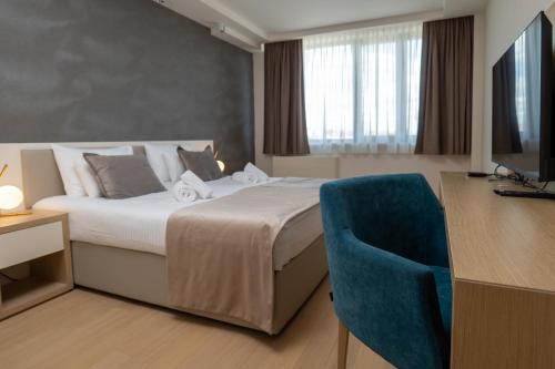a hotel room with a bed and a blue chair at Zepterme Spa&Wellness Luxury Apartments member of Zepter hotels in Vrnjačka Banja