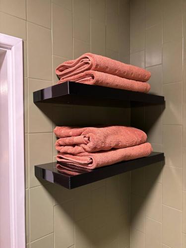 a pile of towels on shelves in a bathroom at Cosy Perth retreat in Perth