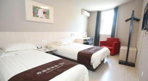 a hotel room with two beds and a red chair at Jinjiang Inn Changchun Xi An Avenue Branch in Changchun
