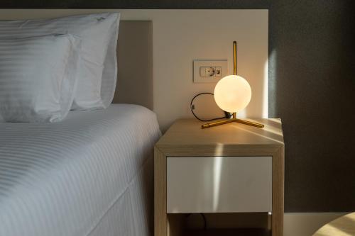 a lamp on a night stand next to a bed at Zepterme Spa&Wellness Luxury Apartments member of Zepter hotels in Vrnjačka Banja