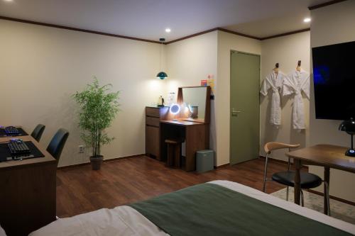 a bedroom with a bed and a desk and a dressing room at Aank Hotel Jeonju in Jeonju
