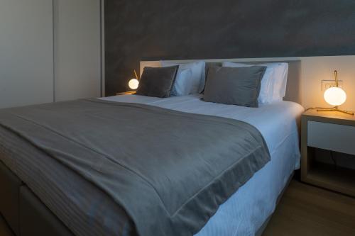 a bedroom with a large bed with two lamps on it at Zepterme Spa&Wellness Luxury Apartments member of Zepter hotels in Vrnjačka Banja