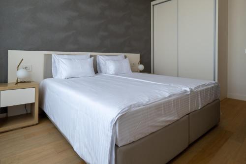 a bedroom with a large bed with white sheets and pillows at Zepterme Spa&Wellness Luxury Apartments member of Zepter hotels in Vrnjačka Banja