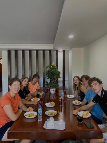 a group of people sitting around a wooden table at Hà Tiên Hạnh Phúc Hotel in Ha Tien