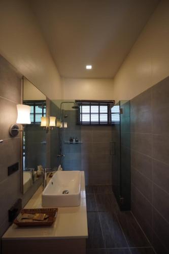 a bathroom with a sink and a glass shower at De Chaochom Hua Hin in Hua Hin