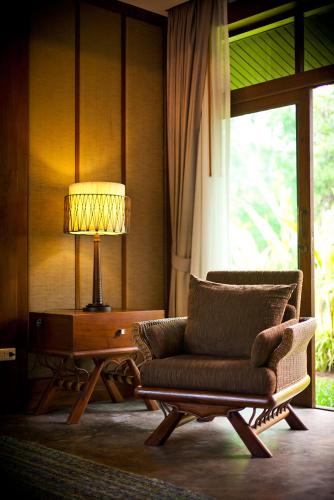 a living room with a chair and a table with a lamp at Sibsan Resort & Spa Maetaeng Chiang Mai in Mae Taeng