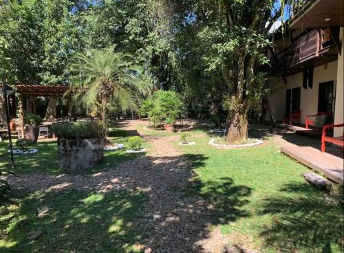 a garden with palm trees and a red bench at Chale Penedo no Centro com Piscina,Hidro e Sauna ! in Itatiaia