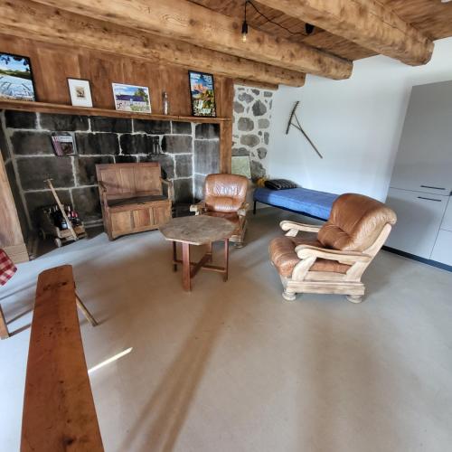 a living room with chairs and a bed and a table at La Grange d'Olivier in Le Claux