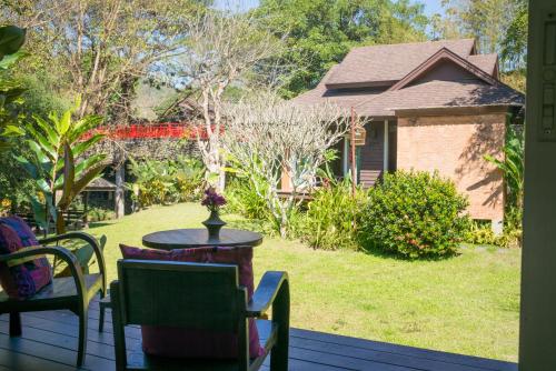 a porch with a table and chairs and a house at Sibsan Resort & Spa Maetaeng Chiang Mai in Mae Taeng