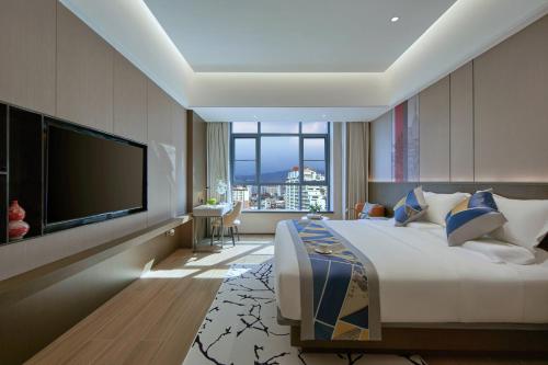 a bedroom with a large bed and a flat screen tv at 西双版纳熙源国际酒店 in Jinghong