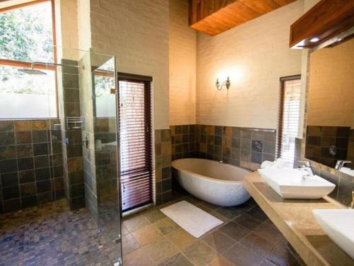 une salle de bain avec une baignoire, un lavabo et une douche dans l'établissement Big Oak Cottages, à Dullstroom