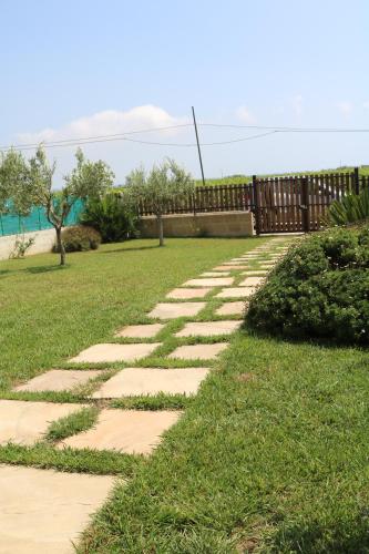 a stone path in the grass with a fence at Villetta Airone in Birgi Vecchi