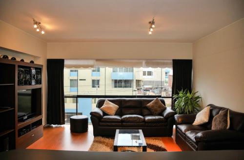 a living room with a leather couch and a large window at Miraflores4Rent Sisley in Lima
