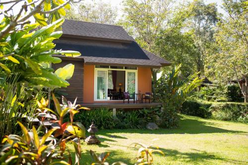 a small house with a deck in a yard at Sibsan Resort & Spa Maetaeng Chiang Mai in Mae Taeng