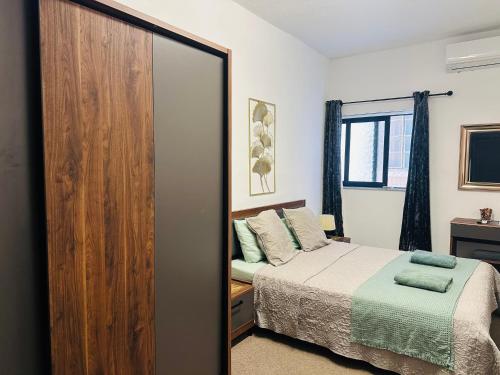a bedroom with a bed and a large wooden closet at Sea Breeze Retreat - Comfort Apartments in the Heart of Sliema in Sliema