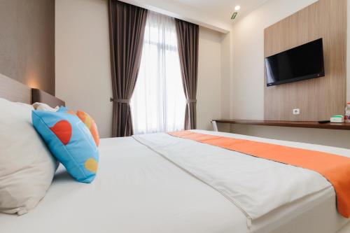 a hotel room with a bed and a television at Sans Vibes Firdaus Mansion Kemang in Jakarta