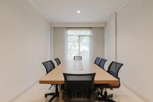 a conference room with a wooden table and chairs at Sans Vibes Firdaus Mansion Kemang in Jakarta