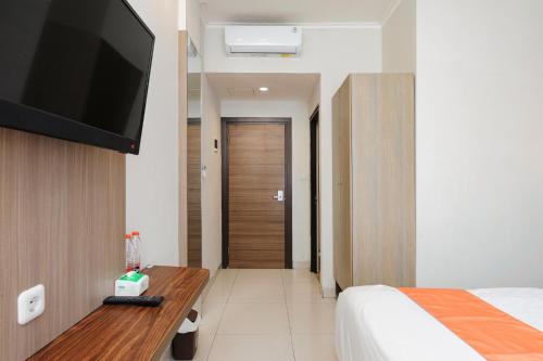 a bedroom with a bed and a television on a wall at Sans Vibes Firdaus Mansion Kemang in Jakarta