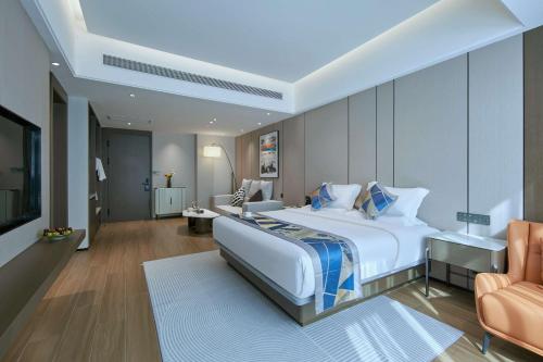 a bedroom with a large white bed and a chair at 西双版纳熙源国际酒店 in Jinghong